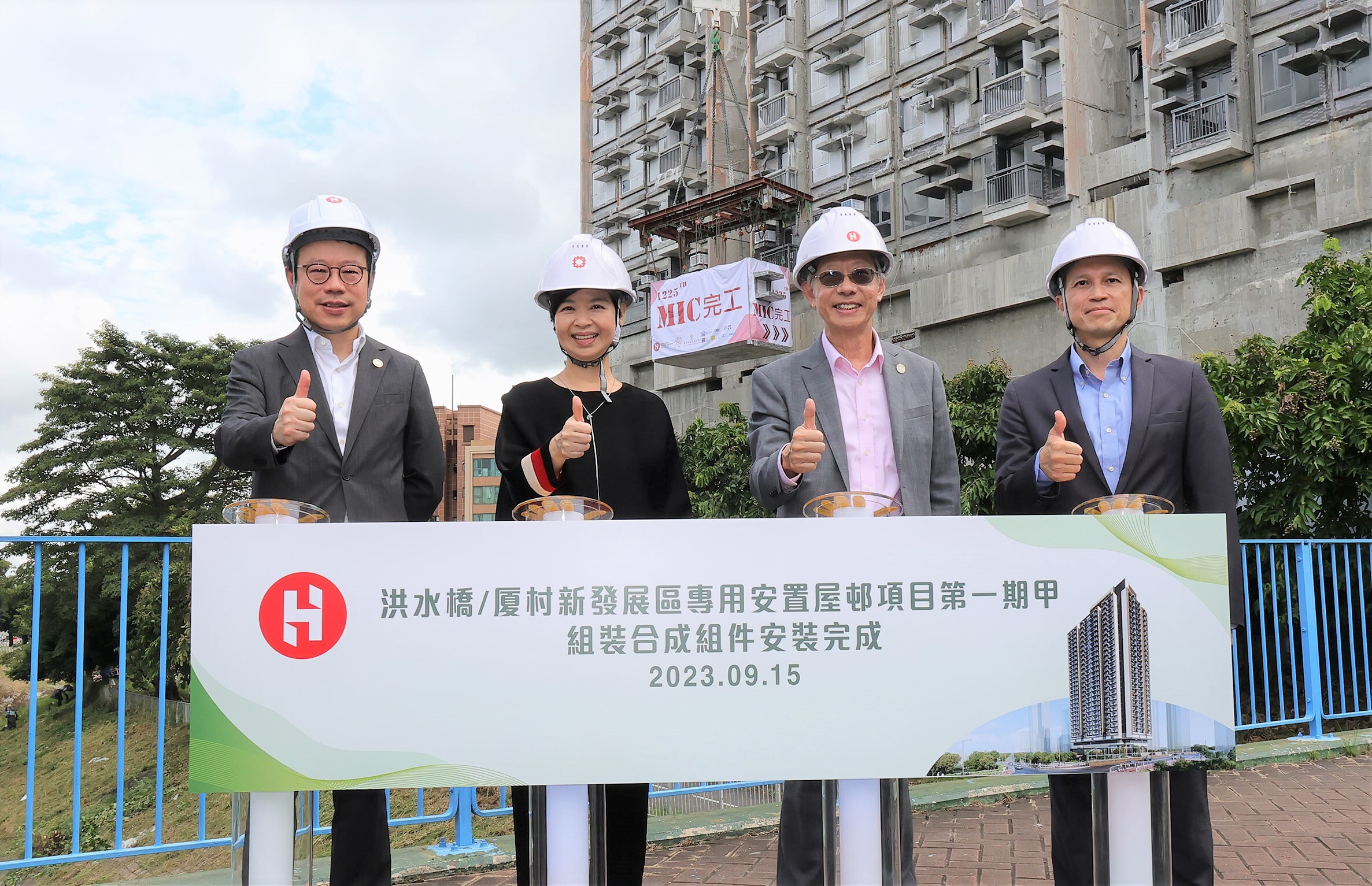 房屋局局長何永賢（左二）及發展局首席助理秘書長 (工務) 馮耀文（右一），房協主席陳家樂（右二）和房協行政總裁陳欽勉（左一）於現場啟動最後一個「組裝合成」組件的吊裝工作。