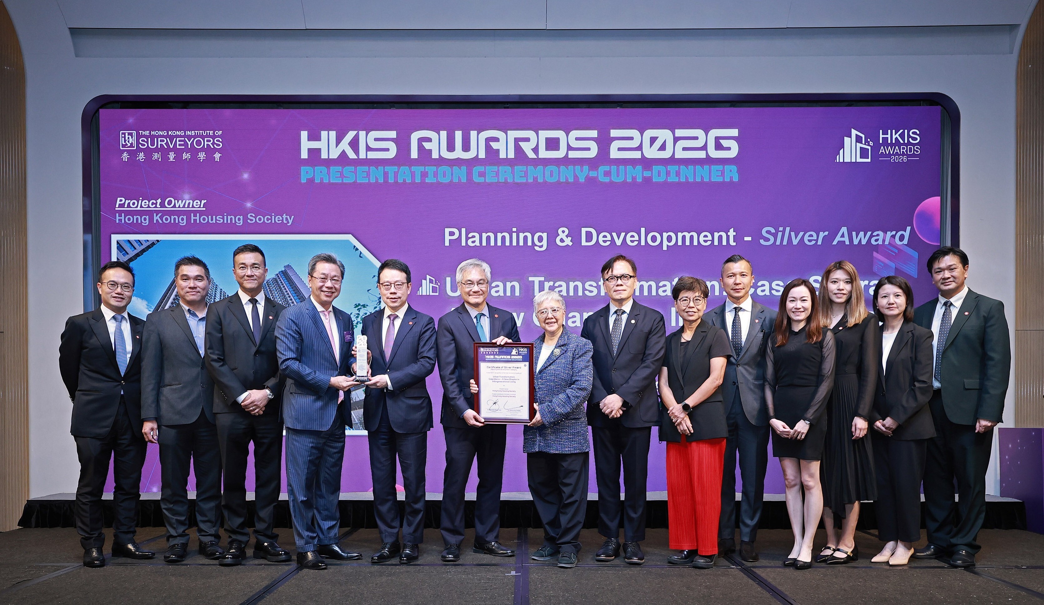 房協專用安置屋邨項目「樂嶺都匯」榮獲「香港測量師學會大獎2026」規劃與發展組別銀獎。房協主席凌嘉勤（左六）、行政總裁陳欽勉（左五）、總監（項目策劃及管理）張冠華（左三）及助理總監（項目管理）黃偉業（右五）等代表領獎。