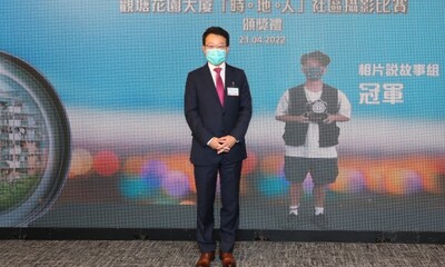 房協行政總裁陳欽勉頒獎予「相片說故事組」冠軍得主，作品以簡潔構圖，捕捉了球場地面水中的花園大廈倒影。