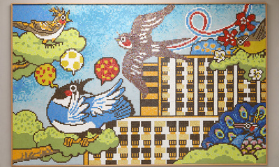 《花園見鴻鵠  鄰里樂安居》馬賽克壁畫設計靈感源自觀塘花園大廈（二期）五座「雀仔樓」，活現百靈、喜鵲、燕子、孔雀及畫眉（左至右），傳承屋邨的集體回憶。